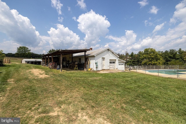 rear view of house with a fenced in pool, a lawn, and an outbuilding