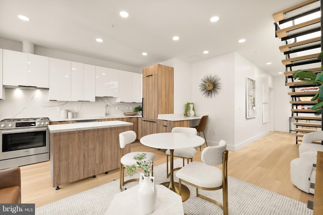 kitchen with tasteful backsplash, light countertops, white cabinets, modern cabinets, and gas range