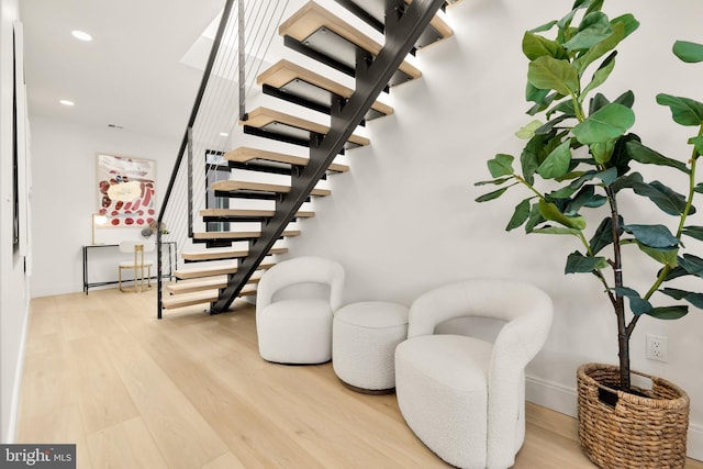 stairs with wood finished floors and recessed lighting