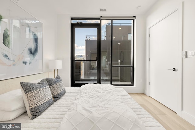 bedroom with access to exterior, visible vents, and wood finished floors