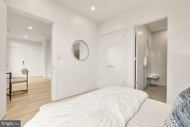 bedroom featuring baseboards, light wood-type flooring, ensuite bathroom, and recessed lighting