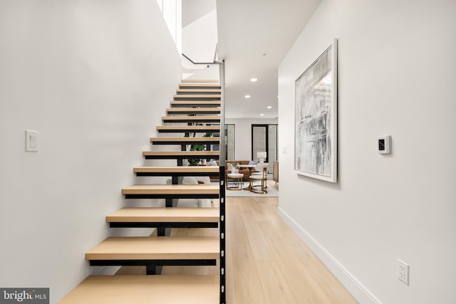 stairway featuring baseboards, wood finished floors, and recessed lighting