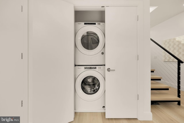 washroom with laundry area, light wood finished floors, and stacked washing maching and dryer