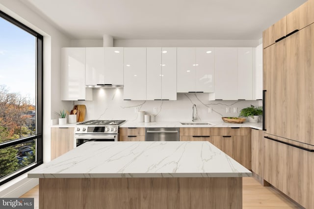 kitchen featuring light stone counters, stainless steel appliances, a sink, white cabinetry, and modern cabinets