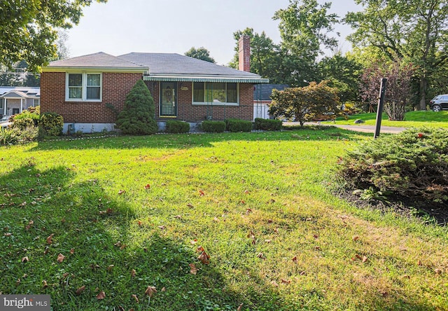 view of front facade with brick siding, a chimney, and a front yard