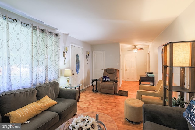 living room with a ceiling fan, arched walkways, and wood finished floors