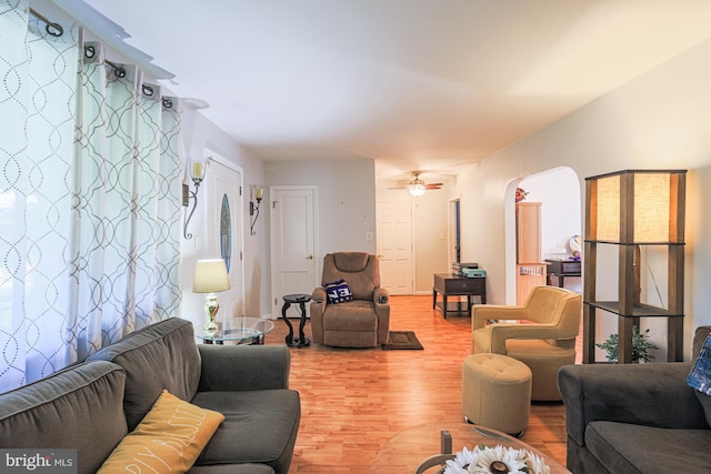 living room featuring arched walkways, ceiling fan, and wood finished floors