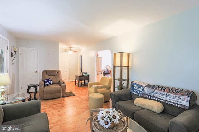 living area featuring arched walkways, ceiling fan, and wood finished floors