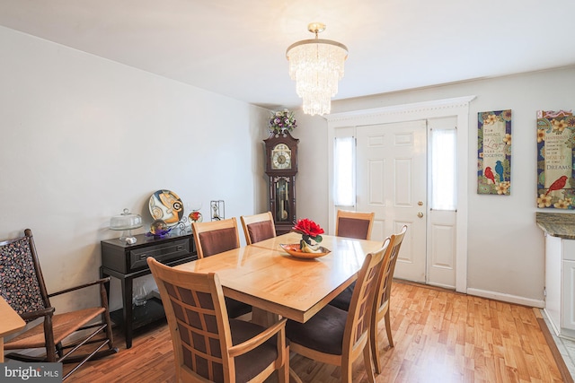 dining space featuring light wood-type flooring, baseboards, and a chandelier