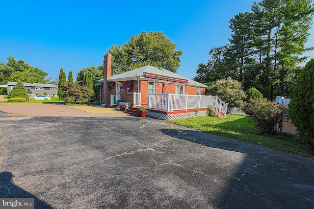 view of front of home with a chimney, a deck, decorative driveway, and brick siding