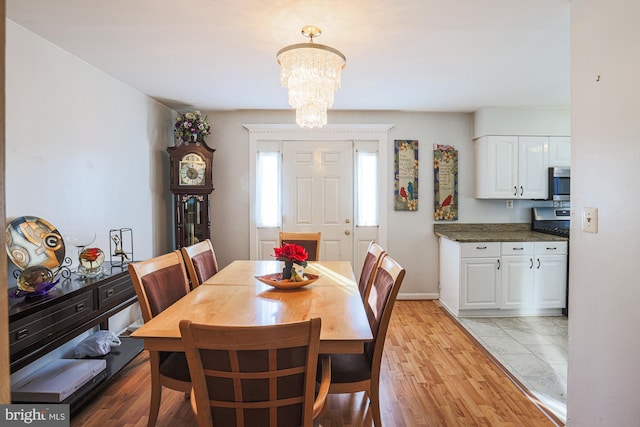 dining space featuring baseboards, light wood-type flooring, and a notable chandelier