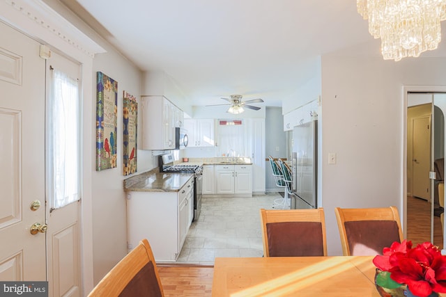 kitchen with ceiling fan with notable chandelier, stainless steel appliances, a healthy amount of sunlight, and white cabinets