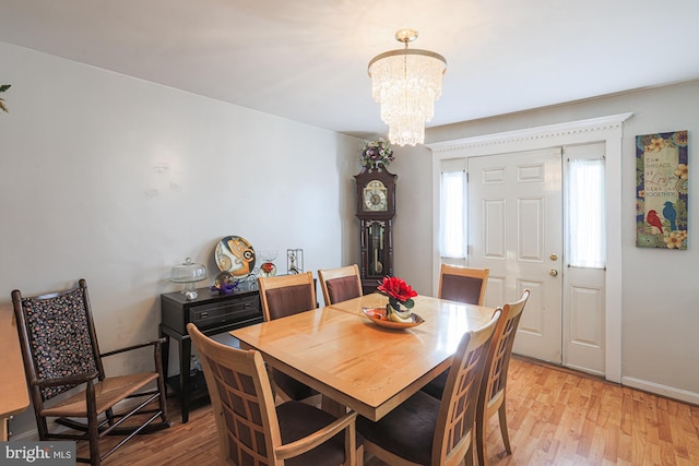 dining room featuring baseboards, light wood-style flooring, and an inviting chandelier