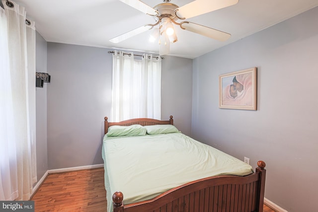 bedroom with a ceiling fan, baseboards, and wood finished floors