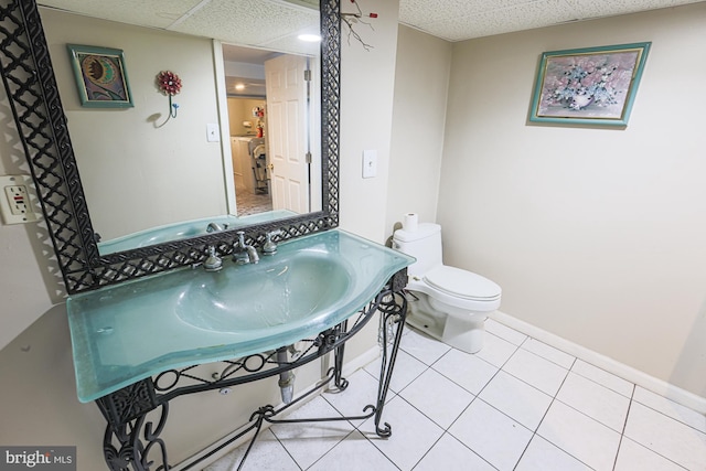 bathroom featuring toilet, tile patterned flooring, a paneled ceiling, and baseboards