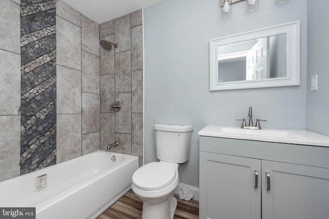 full bathroom featuring hardwood / wood-style flooring, vanity, tiled shower / bath combo, and toilet