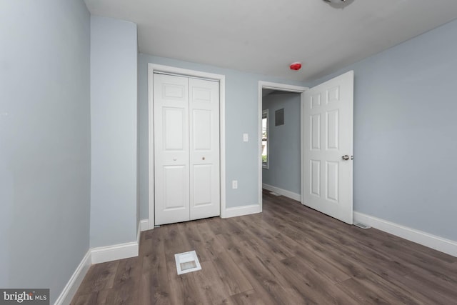 unfurnished bedroom featuring a closet and dark hardwood / wood-style floors