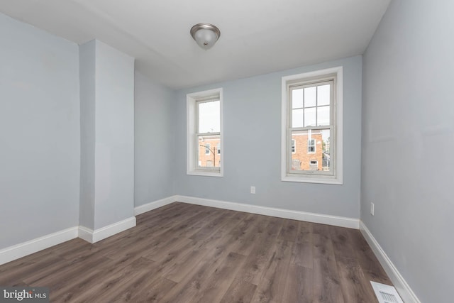 spare room with dark wood-type flooring and a wealth of natural light