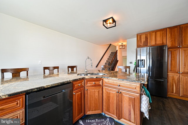 kitchen featuring dishwasher, dark hardwood / wood-style flooring, sink, stainless steel fridge with ice dispenser, and a breakfast bar