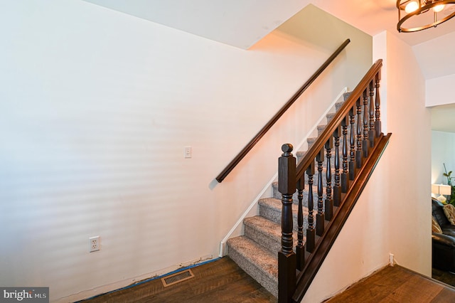 stairs featuring hardwood / wood-style floors and a notable chandelier