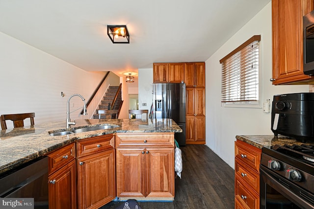 kitchen featuring dark stone counters, stainless steel appliances, a kitchen breakfast bar, dark hardwood / wood-style flooring, and sink