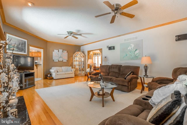 living area with light wood-style flooring, ornamental molding, visible vents, a textured ceiling, and ceiling fan