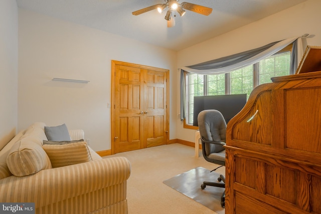 office area featuring baseboards, ceiling fan, and light carpet