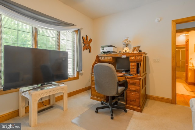 home office with plenty of natural light and light carpet