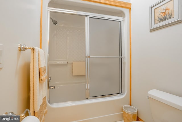 bathroom with toilet and bath / shower combo with glass door