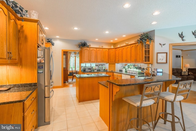 kitchen with a sink, a breakfast bar area, a peninsula, and freestanding refrigerator