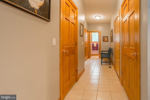 corridor with baseboards and light tile patterned floors