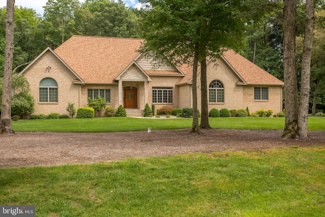 view of front of home featuring brick siding, a shingled roof, and a front yard