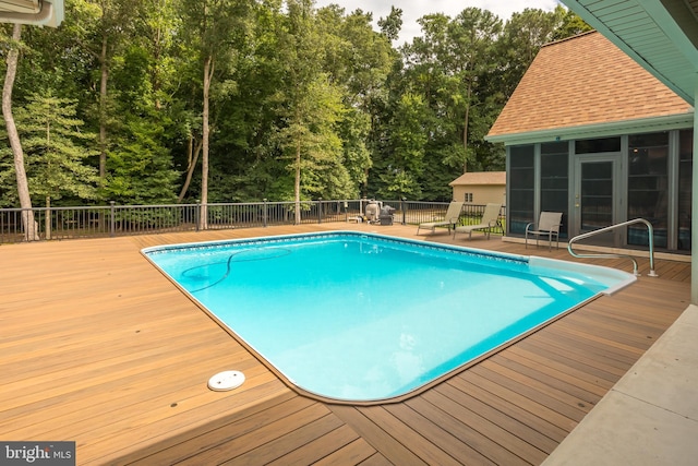 view of swimming pool featuring fence, a fenced in pool, a wooden deck, and a sunroom