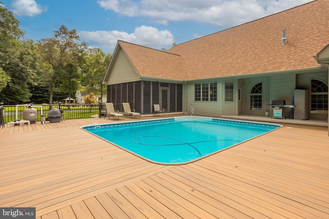 view of pool with a wooden deck, a grill, and a sunroom