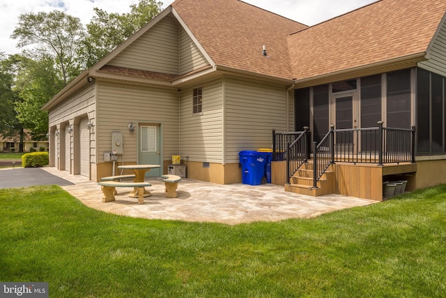 rear view of property with a sunroom, a yard, driveway, roof with shingles, and a garage