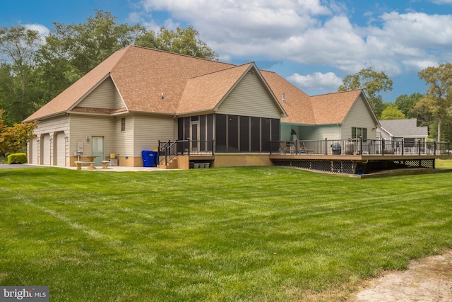 rear view of house featuring a garage, a deck, a sunroom, and a lawn