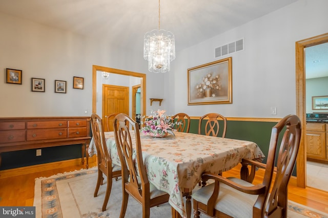 dining area with light hardwood / wood-style flooring and a chandelier