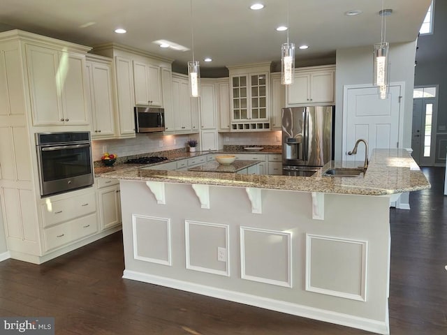 kitchen featuring a spacious island, stainless steel appliances, dark wood-type flooring, and a sink