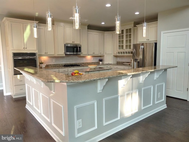 kitchen featuring stainless steel appliances, dark wood-type flooring, a large island, a kitchen bar, and tasteful backsplash