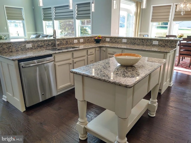 kitchen featuring a kitchen island, dark wood finished floors, stainless steel dishwasher, plenty of natural light, and a sink