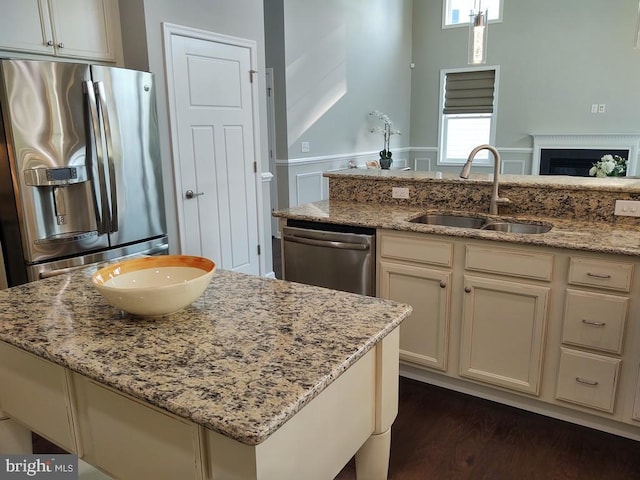 kitchen with appliances with stainless steel finishes, light stone countertops, a fireplace, and a sink