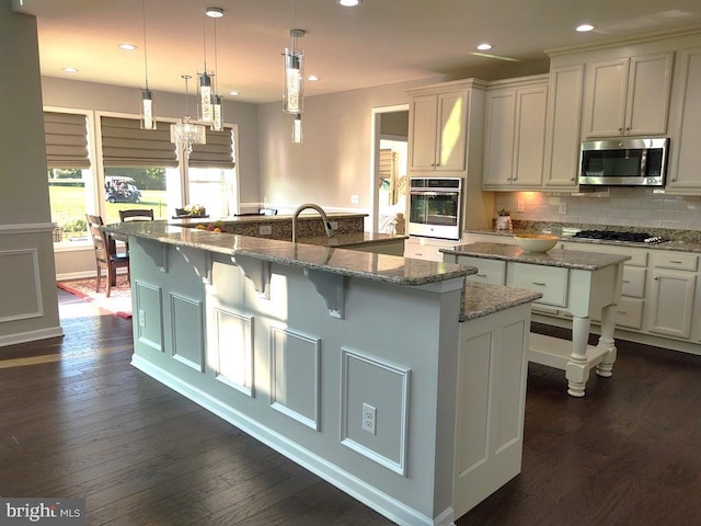 kitchen featuring backsplash, dark wood finished floors, recessed lighting, a large island with sink, and appliances with stainless steel finishes