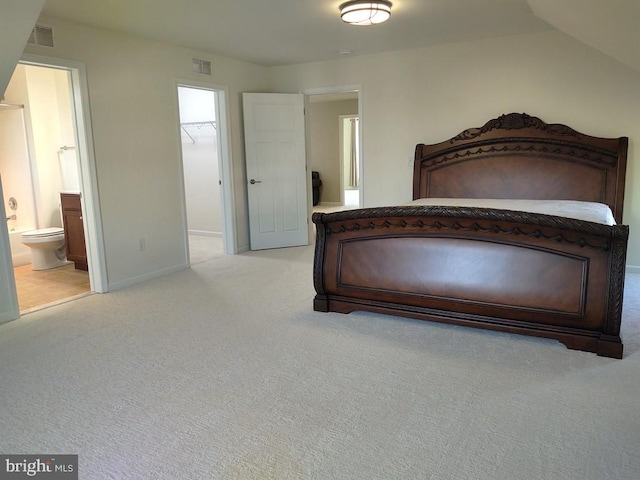 unfurnished bedroom with a walk in closet, light colored carpet, visible vents, and baseboards