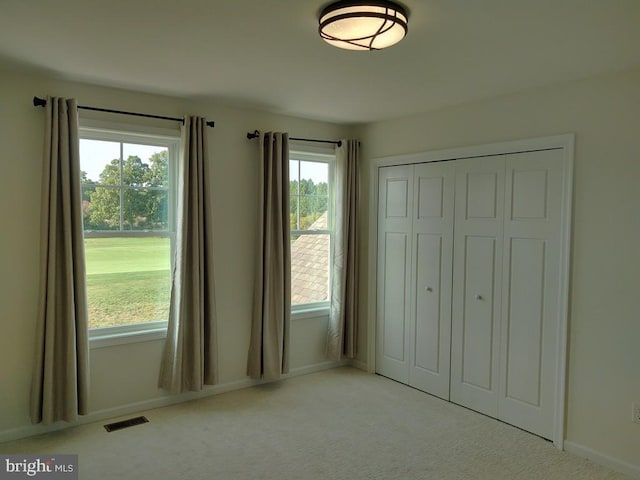 unfurnished bedroom with carpet, visible vents, a closet, and baseboards