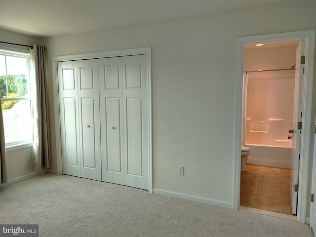 unfurnished bedroom with multiple windows, a closet, carpet floors, and connected bathroom