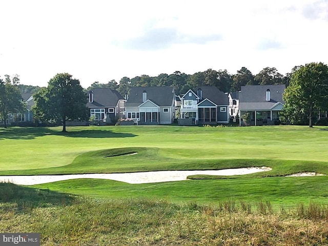 view of home's community with view of golf course and a lawn