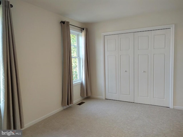 unfurnished bedroom featuring visible vents, carpet flooring, baseboards, and multiple windows