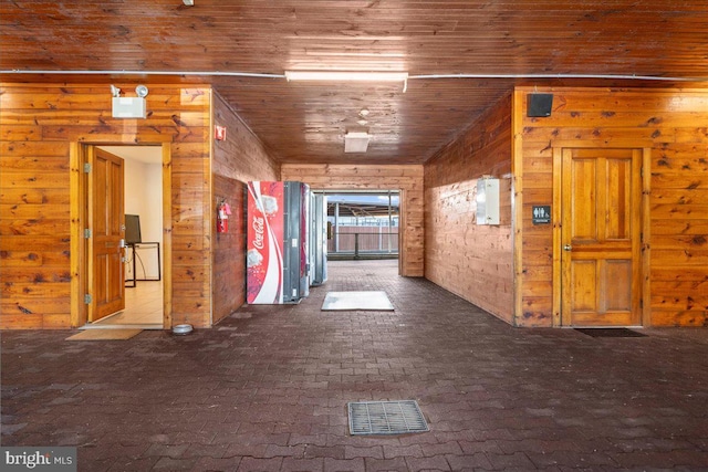 interior space featuring visible vents, wood walls, wooden ceiling, and brick floor