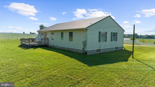 view of home's exterior with metal roof, a lawn, a deck, and fence