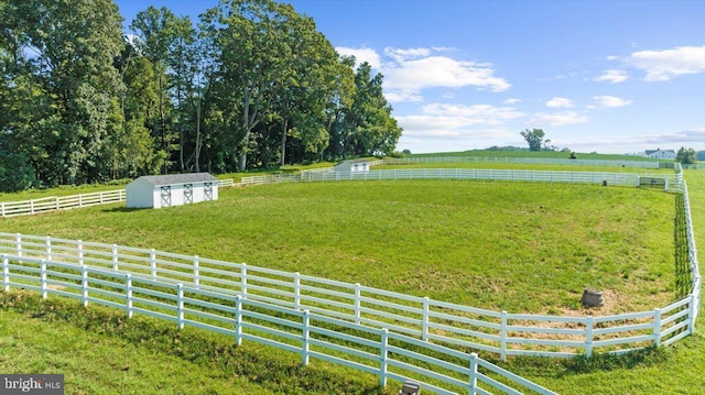 view of yard with an outbuilding, a rural view, a storage shed, and fence